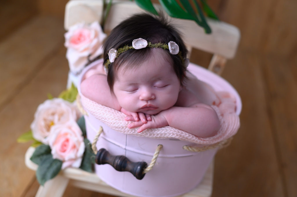 Bebê dentro de um baldinho rosa com flores e plantas | Ensaio Newborn em Caruaru